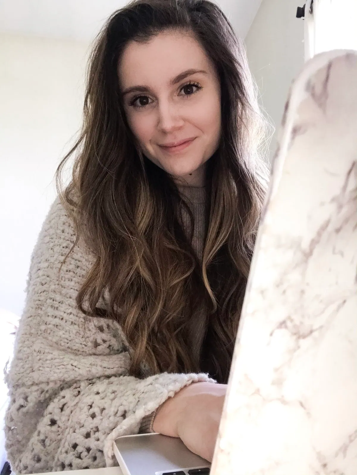Cydney Marlene at her desk, wearing a cream knit sweater